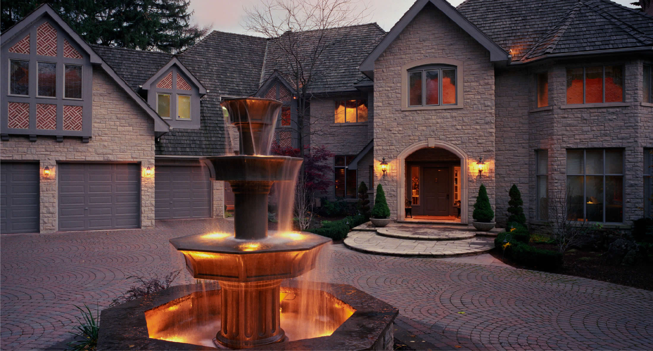 A stone home with warm evening light and a landscaped courtyard